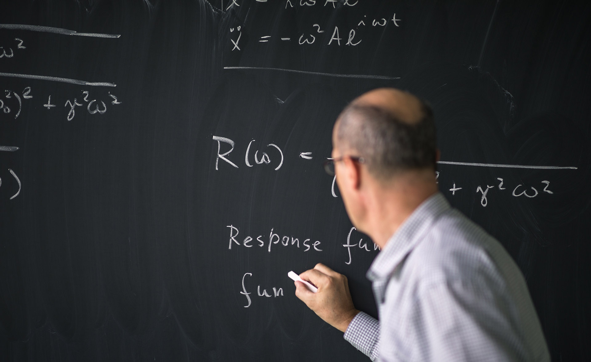 En lärare står och skriver på svarta tavlan.