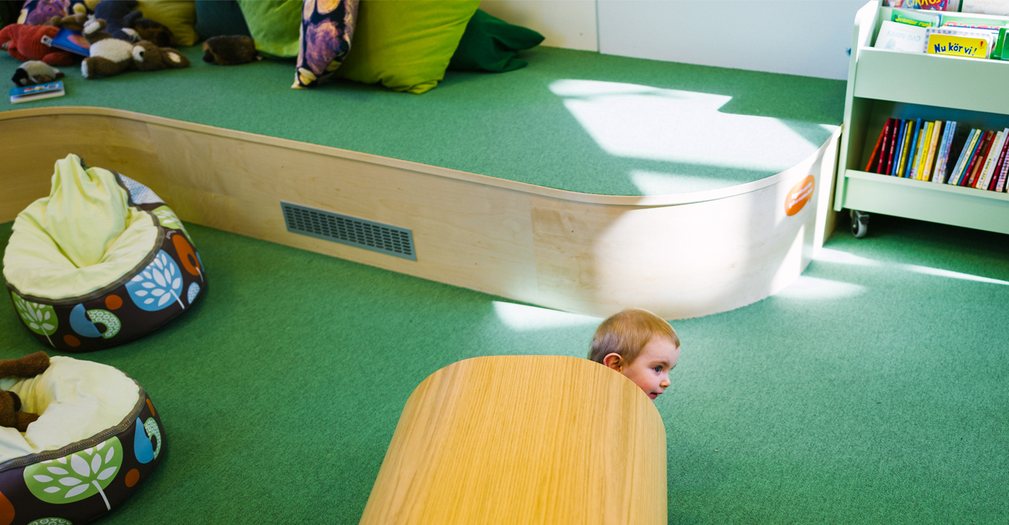Bebis som kikar fram från en lektunnel på ett grönt golv.