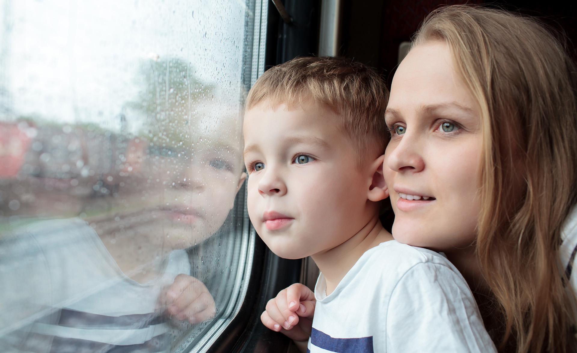 Ett barn och en mamma tittar ut genom ett tågfönster