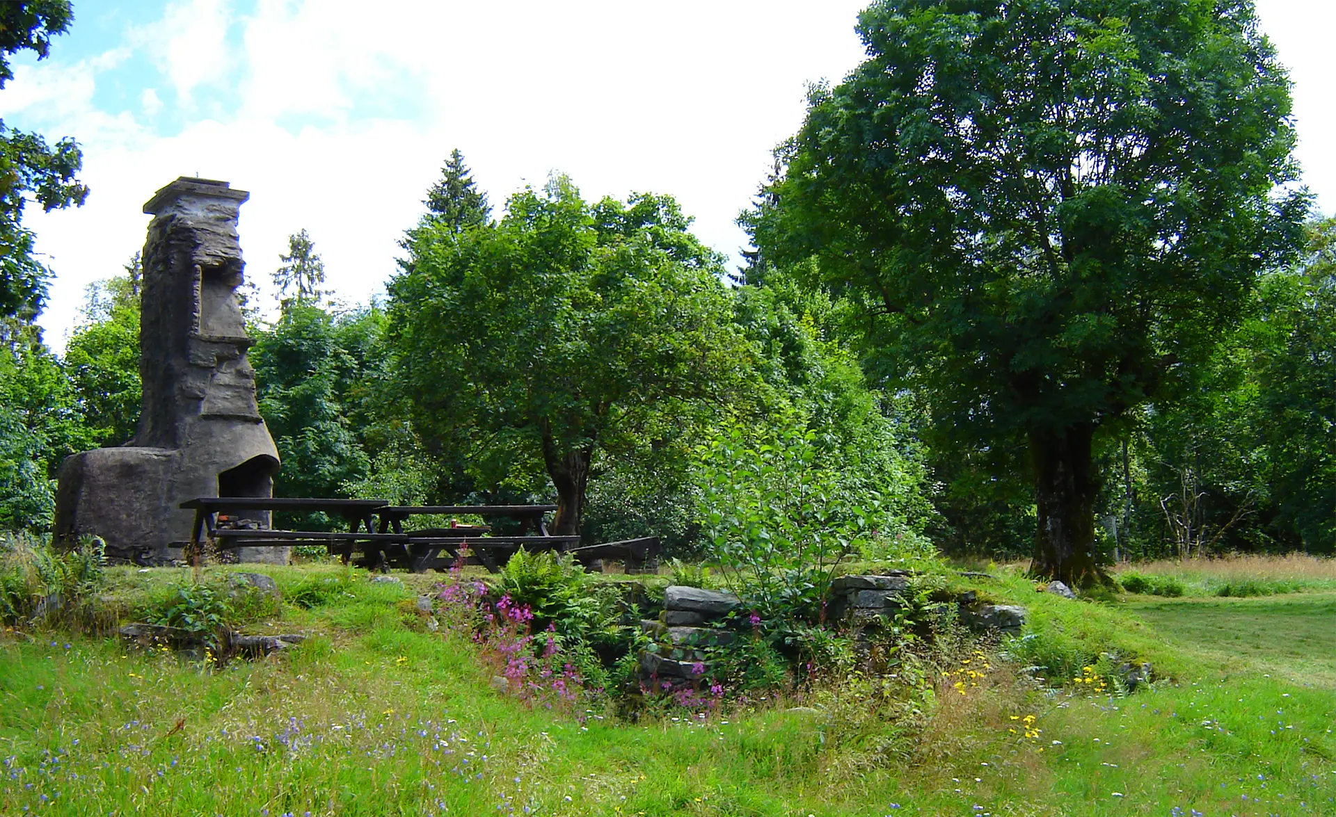 Ett naturreservat med rester av en gammal husruin. Den murade skorstenen finns kvar. 