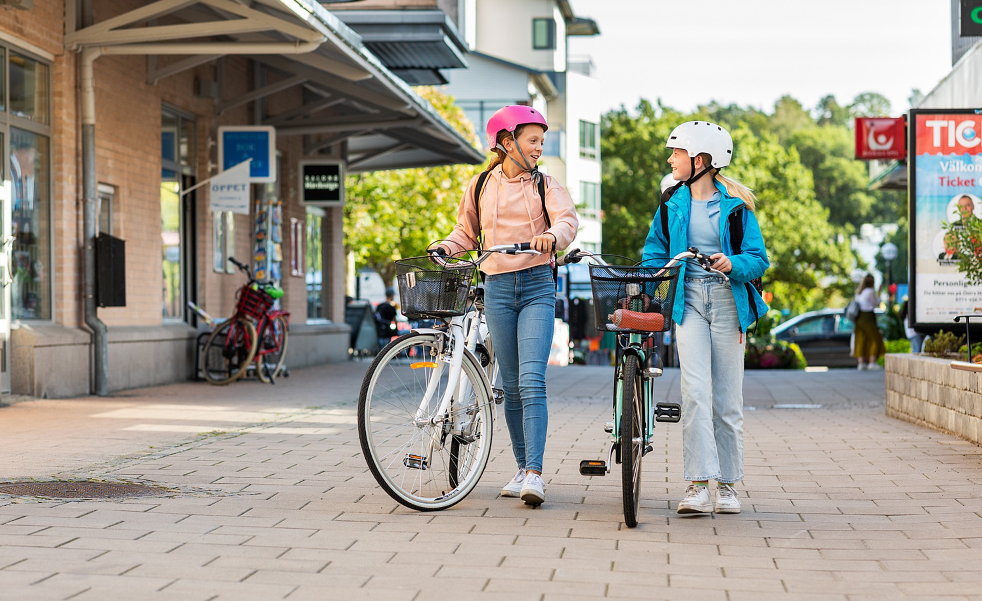 Tjejer går med varsin cykel i Mölnlycke centrum.