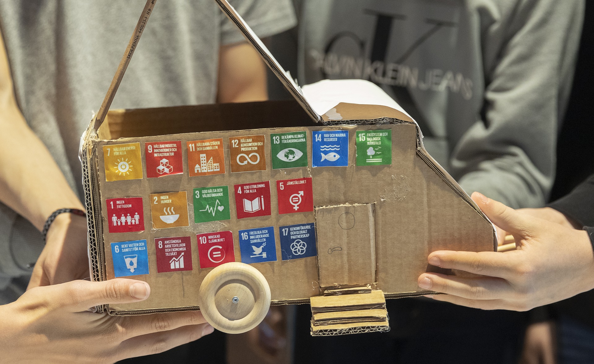 Barnhänder håller i en kartongmodell med bilder på de globala målen. 