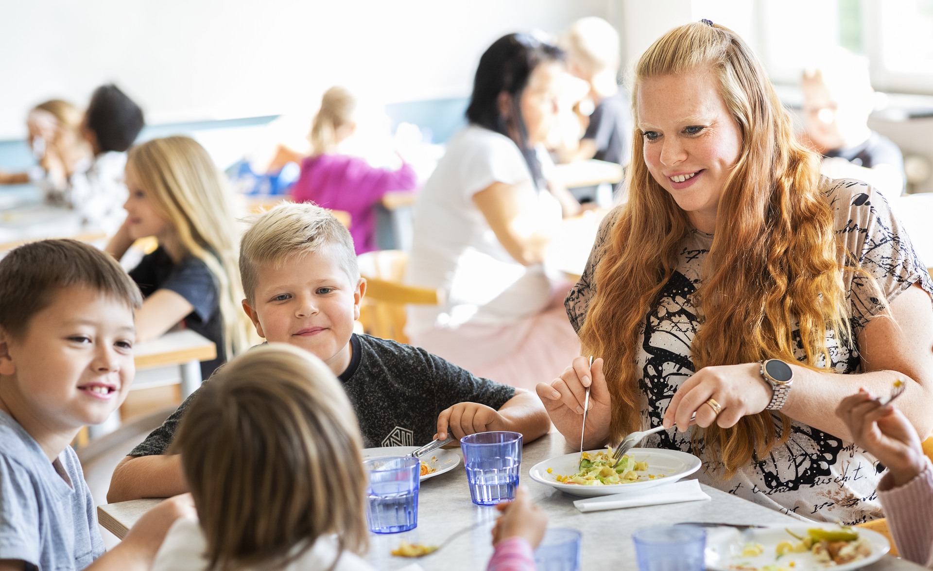 Lärare och elever äter och samtalar tillsammans i skolrestaurang.