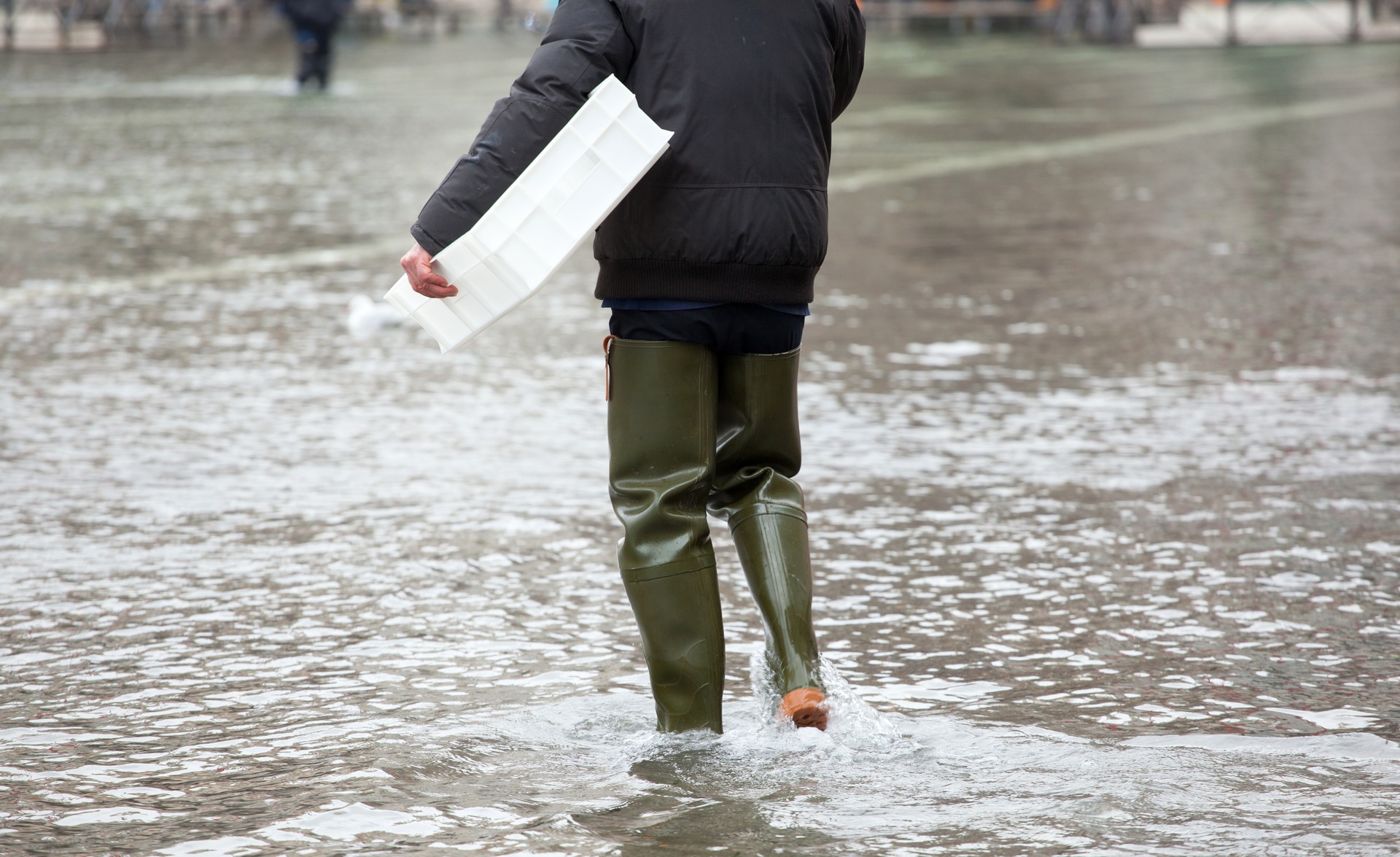 Person som går i vadarstövlar på översvämmad gata.
