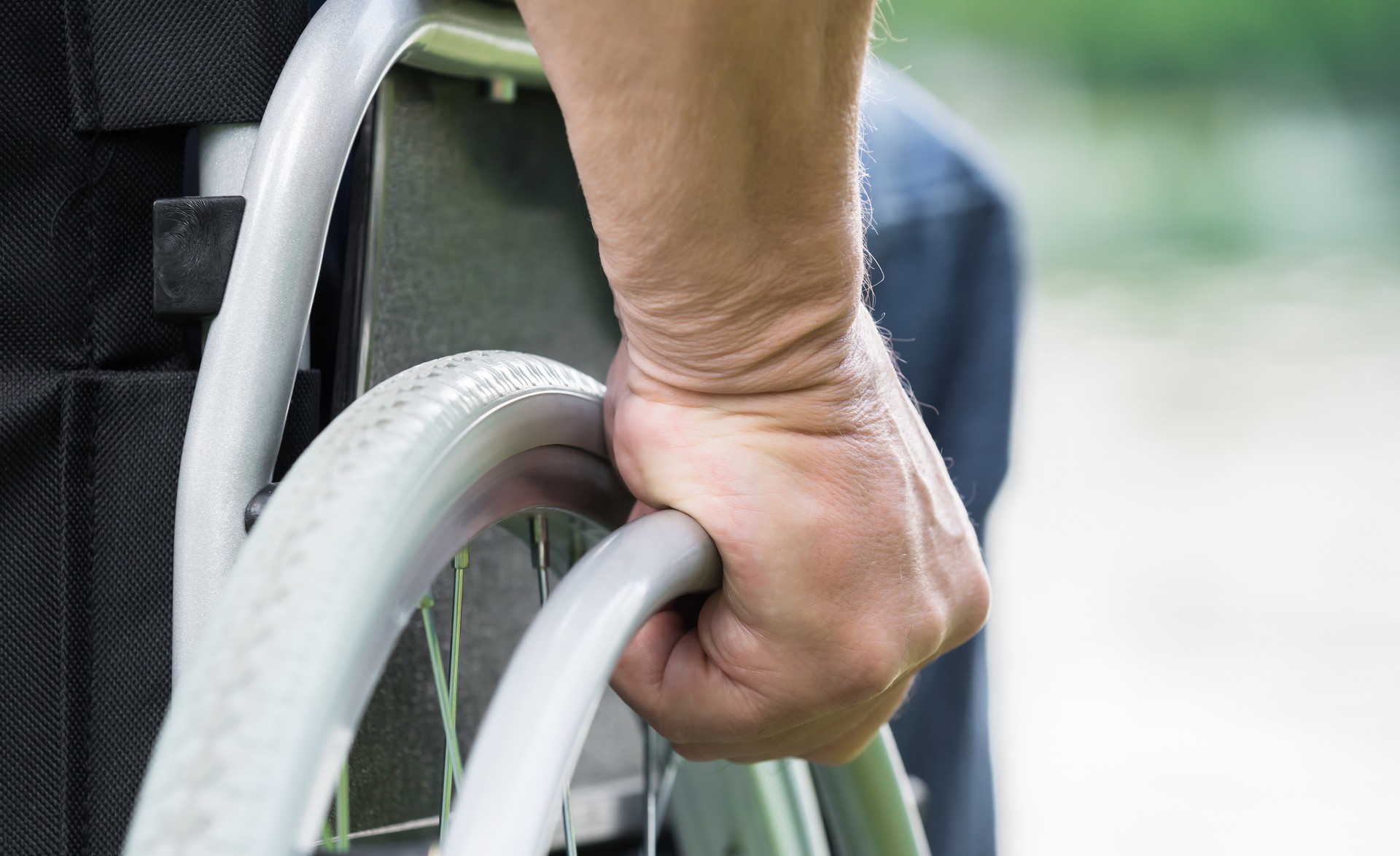 Close-up Of A Disabled Man Pushing Wheel Of Wheelchair