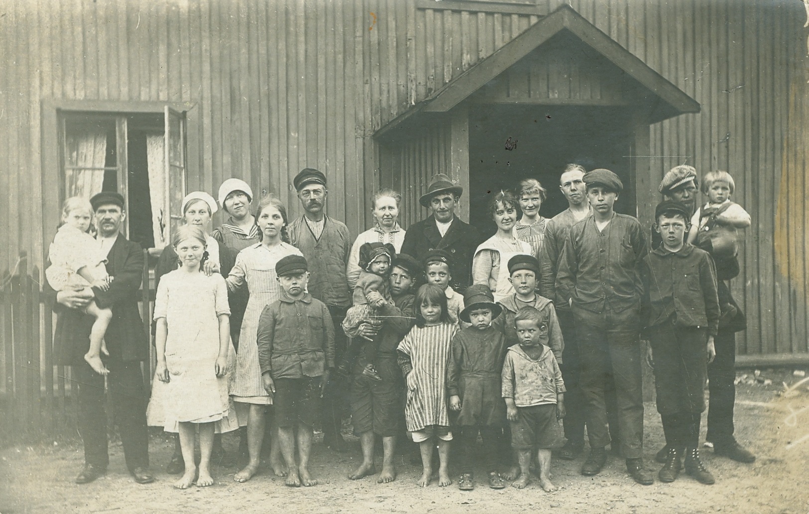 Arbetarfamiljer framför huset Värmland - en av Mölnlycke fabrikers arbetarbostäder. Året är 1921.