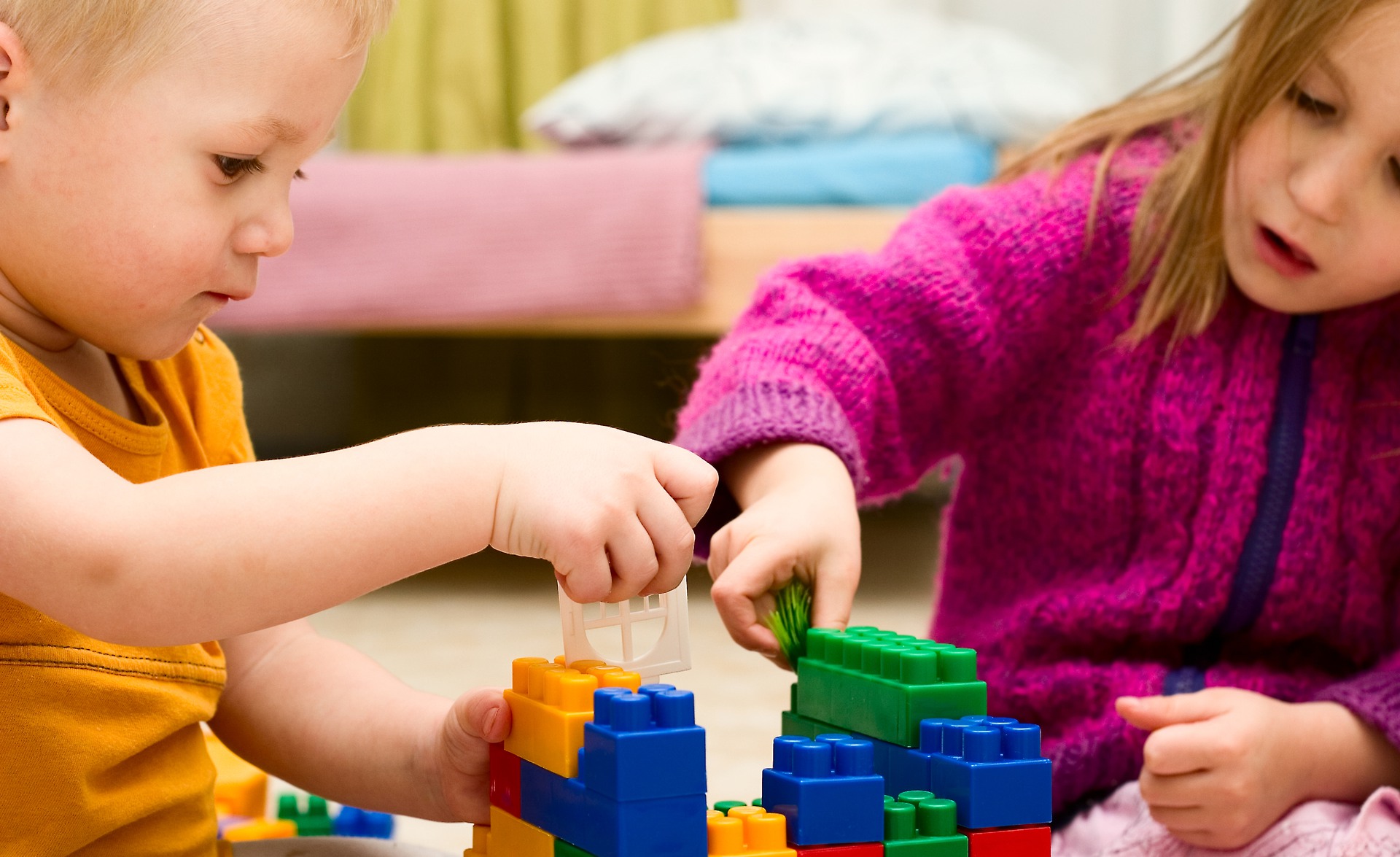 Två barn hjälps åt att bygga hus av lekklossar